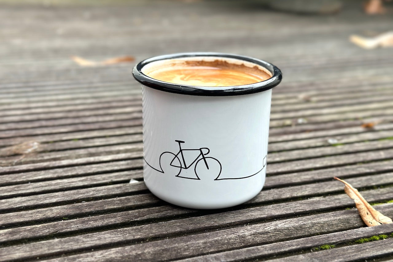 Eine Emaille-Kaffeetasse in weiß mit einem Fahrrad