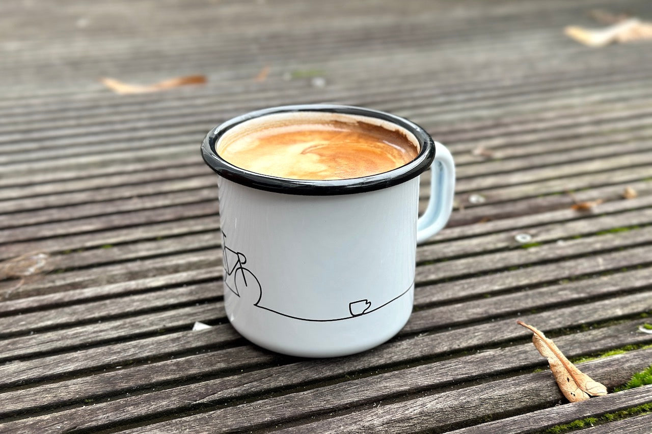 Eine Emaille-Kaffeetasse in weiß mit einem Fahrrad